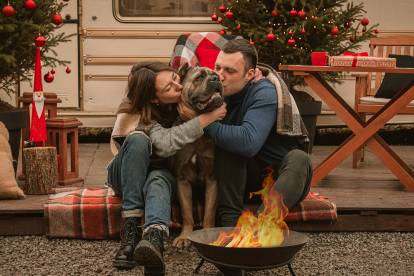 Cane Corso enlacé par un couple assis autour du feu