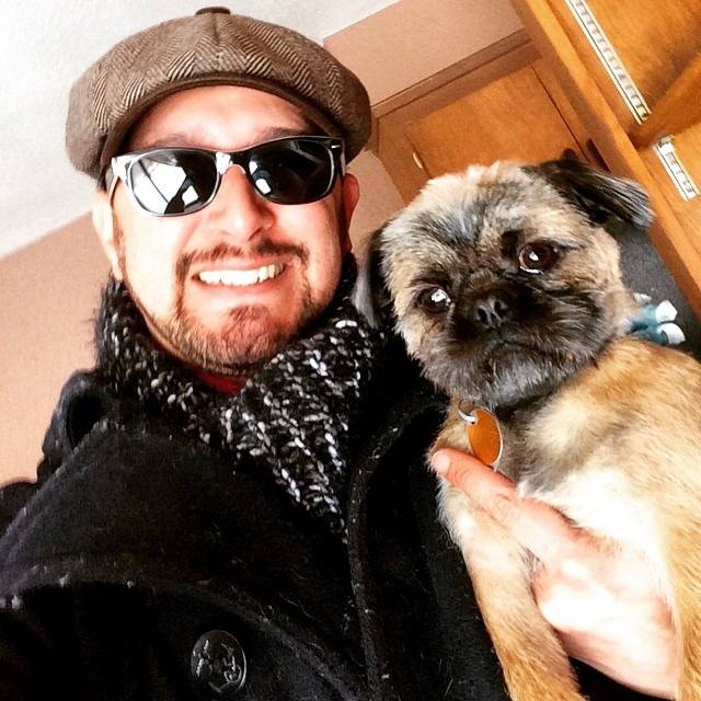 Un Pug Zu faisant face à la caméra et tenu dans les bras d'une personne
