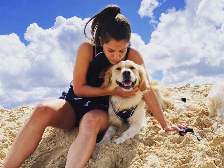 La comportementaliste assise dans le sable avec un chien